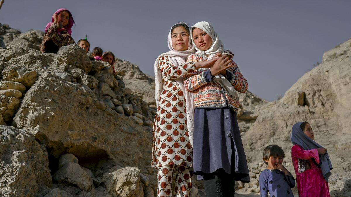 In this picture taken on October 3, 2021, Hazara ethnic people stand on a cliff pockmarked by caves where people still live as they did centuries ago in Bamiyan.