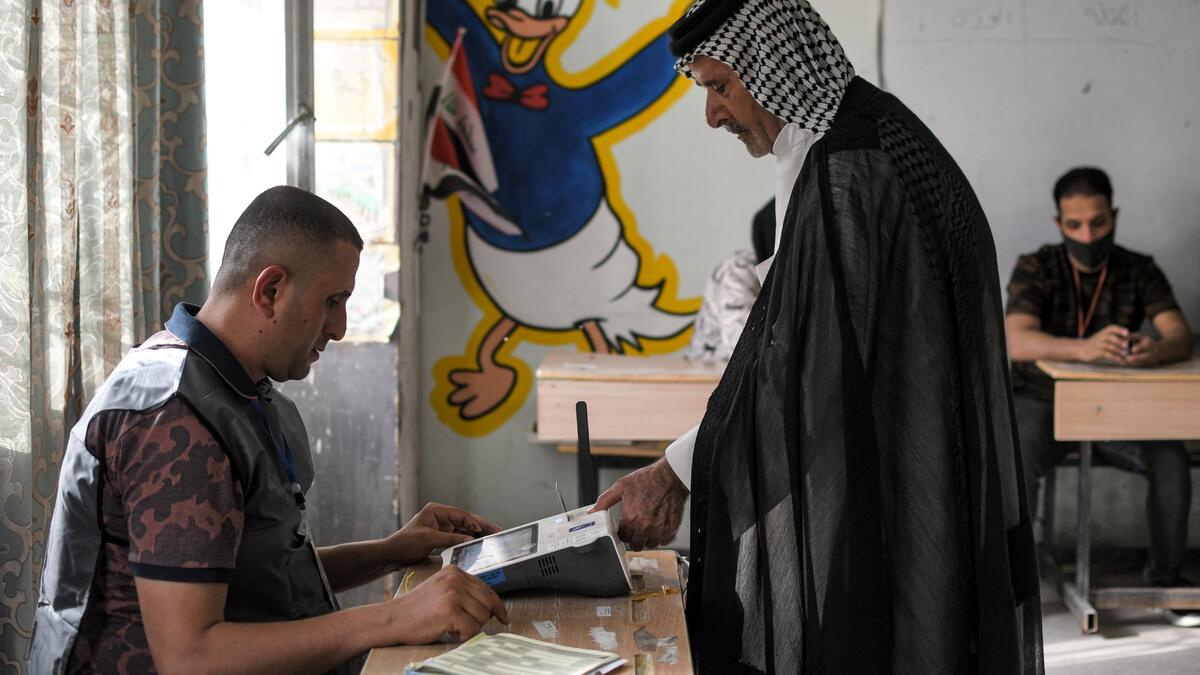 A voter scans his fingerprint a scanner while registering his vote at a polling station in the southern city of Nasiriyah in Iraq's Dhi Qar province, during the early parliamentary elections on October 10, 2021. (Photo by Asaad NIAZI / AFP)
