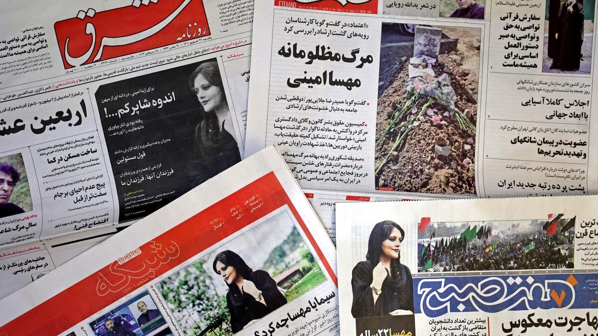 A picture taken in Tehran on September 18, 2022 shows the front pages of Iranian newspapers featuring articles and photographs of Mahsa Amini, a woman who died after being arrested by the Islamic republic's "morality police" two days ago. (Photo by ATTA KENARE / AFP) Mahsa Amini
