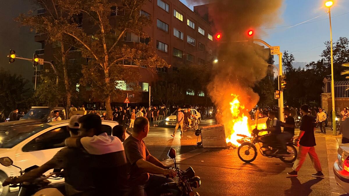 A picture obtained by AFP outside Iran shows demonstrators gathering around a burning barricade during a protest for Mahsa Amini, a woman who died after being arrested by the Islamic republic's "morality police", in Tehran on September 19, 2022. (Photo by AFP) Mahsa Amini