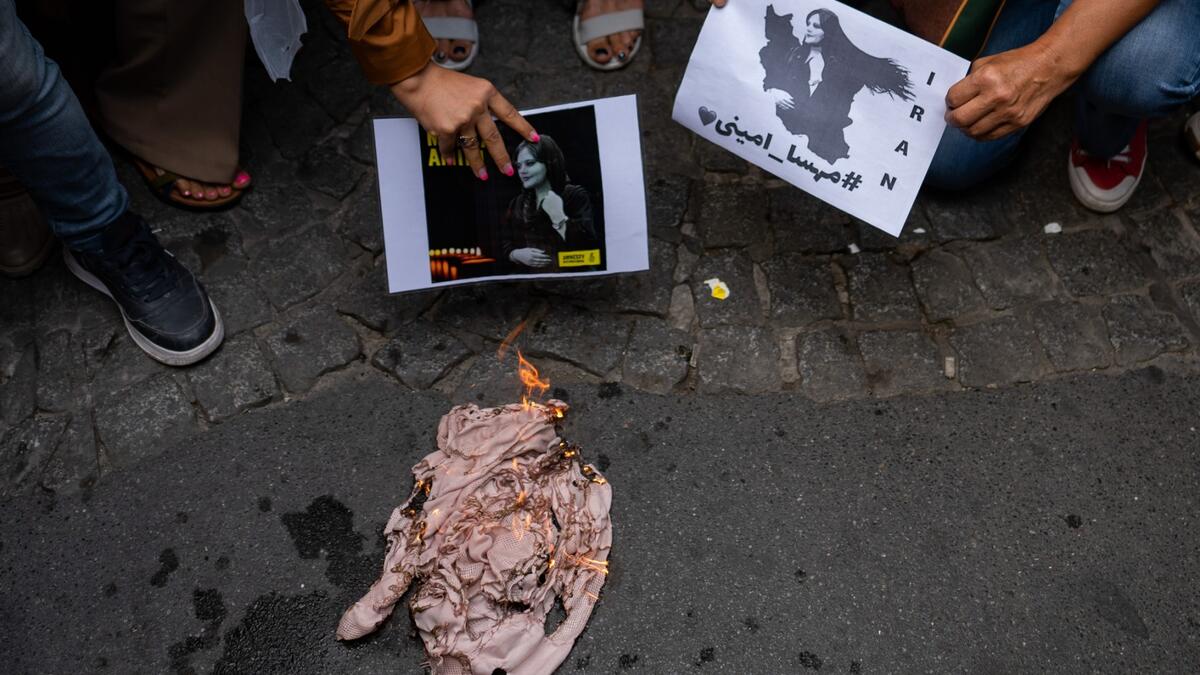 An Iranian woman living in Turkey, burns a headscarf, during a protest outside the Iranian consulate in Istanbul on September 21, 2022, following the death of an Iranian Amini after her arrest by the country's morality police in Tehran. (Photo by Yasin AKGUL / AFP) Mahsa Amini