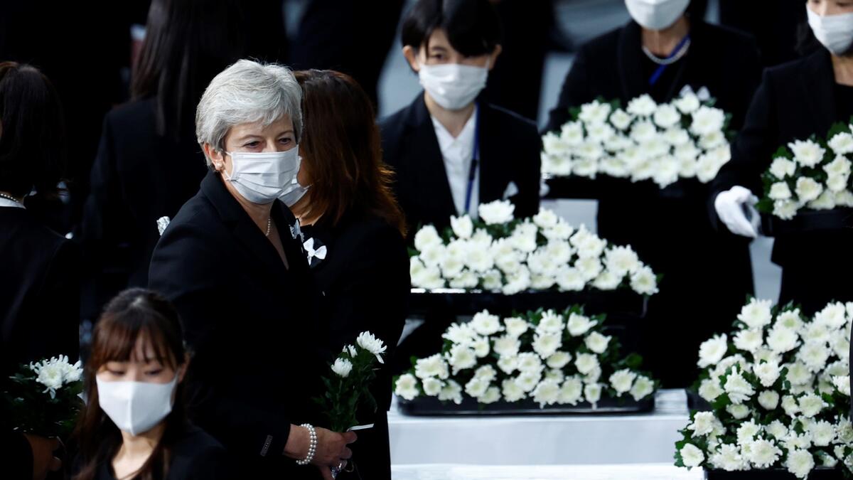 Britain's former prime minister Theresa May (L) prepares to lay flowers during the state funeral for Japan's former prime minister Shinzo Abe in the Nippon Budokan in Tokyo on September 27, 2022. (Photo by KIM KYUNG-HOON / POOL / AFP) Shinzo Abe