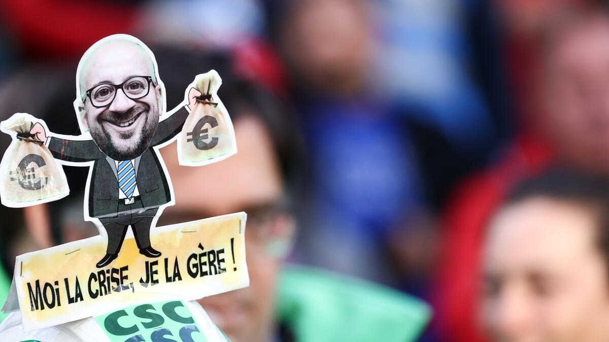 A protester wears an helmet with a caricature of European Council President Charles Michel reading "I'm handling the crisis" during a demonstration against surging energy prices and increased living costs during a national demonstration in Brussels on September 21, 2022. (Photo by Kenzo TRIBOUILLARD / AFP) Energy crisis
