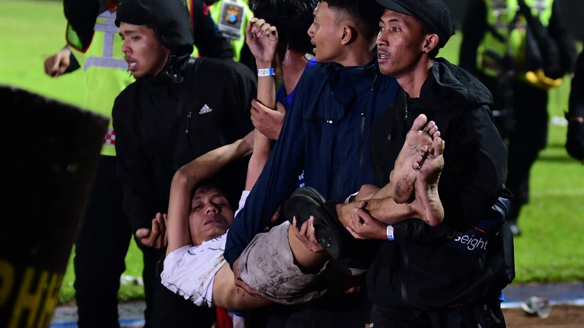 In this picture taken on October 1, 2022, a group of people carry a man after a football match between Arema FC and Persebaya Surabaya at Kanjuruhan stadium in Malang, East Java. (Photo by AFP) Indonesia's football stadium