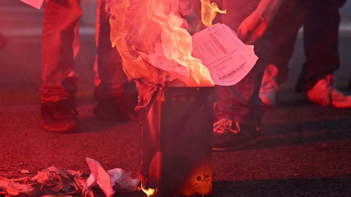 Protestors burn up their energy bills during a demonstration organized by Italian's Unione Sindacale di Base (USB) against the high cost of living and energy price rising in Rome on October 3, 2022. (Photo by Alberto PIZZOLI / AFP) Energy crisis