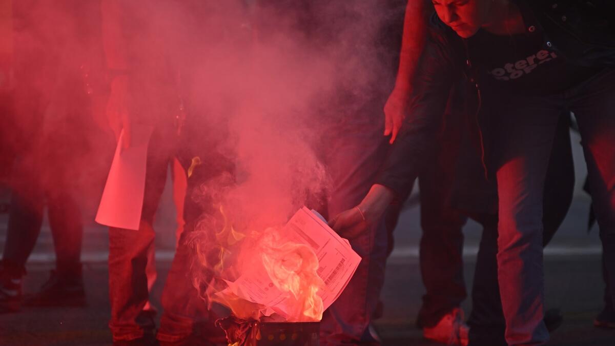 People from the USB union "Unione Sindacale di Base" burn their energy bills during a demonstration over the cost-of-living crisis especially the energy prices rising in central Rome, on October 3, 2022. (Photo by Alberto PIZZOLI / AFP) Energy crisis