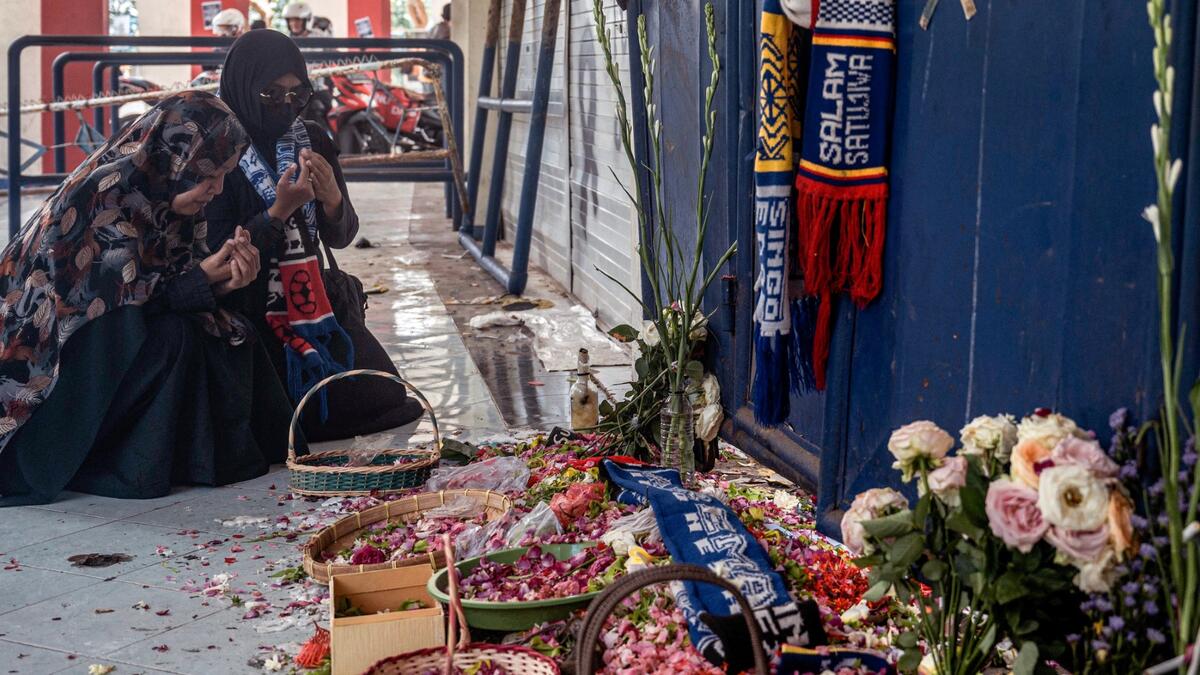 People pay their respects for victims of the stampede at Kanjuruhan stadium in Malang, East Java on October 4, 2022.  (Photo by JUNI KRISWANTO / AFP) Indonesia's football stadium