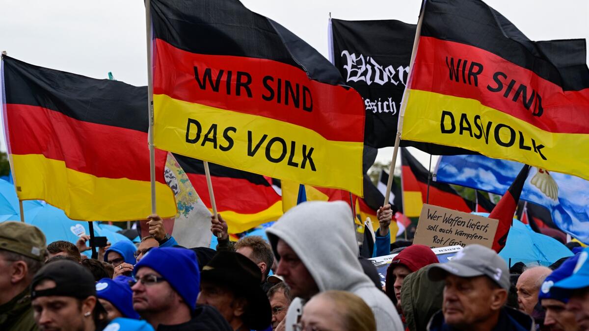 Protesters hold German flags with "We are the people" written on them during a rally of far-right groups including the Alternative for Germany (AfD) party against rising prices in Berlin on October 8, 2022. (Photo by John MACDOUGALL / AFP) Energy crisis
