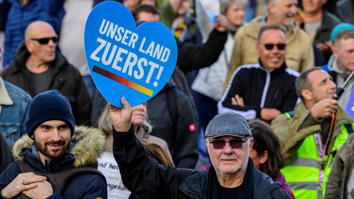 A protester holds up a sign reading: "Our country first" during a rally of far-right groups including the Alternative for Germany (AfD) party against rising prices in Berlin on October 8, 2022. (Photo by John MACDOUGALL / AFP) Energy crisis