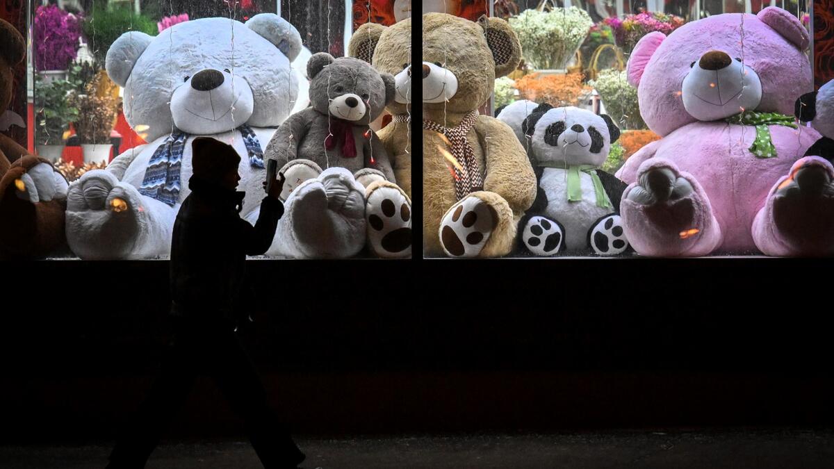 A pedestrian walks past a shop window with teddy bears as decoration ahead of the New Year and Christmas festivities in Moscow on December 26, 2022. (Photo by Yuri KADOBNOV / AFP)