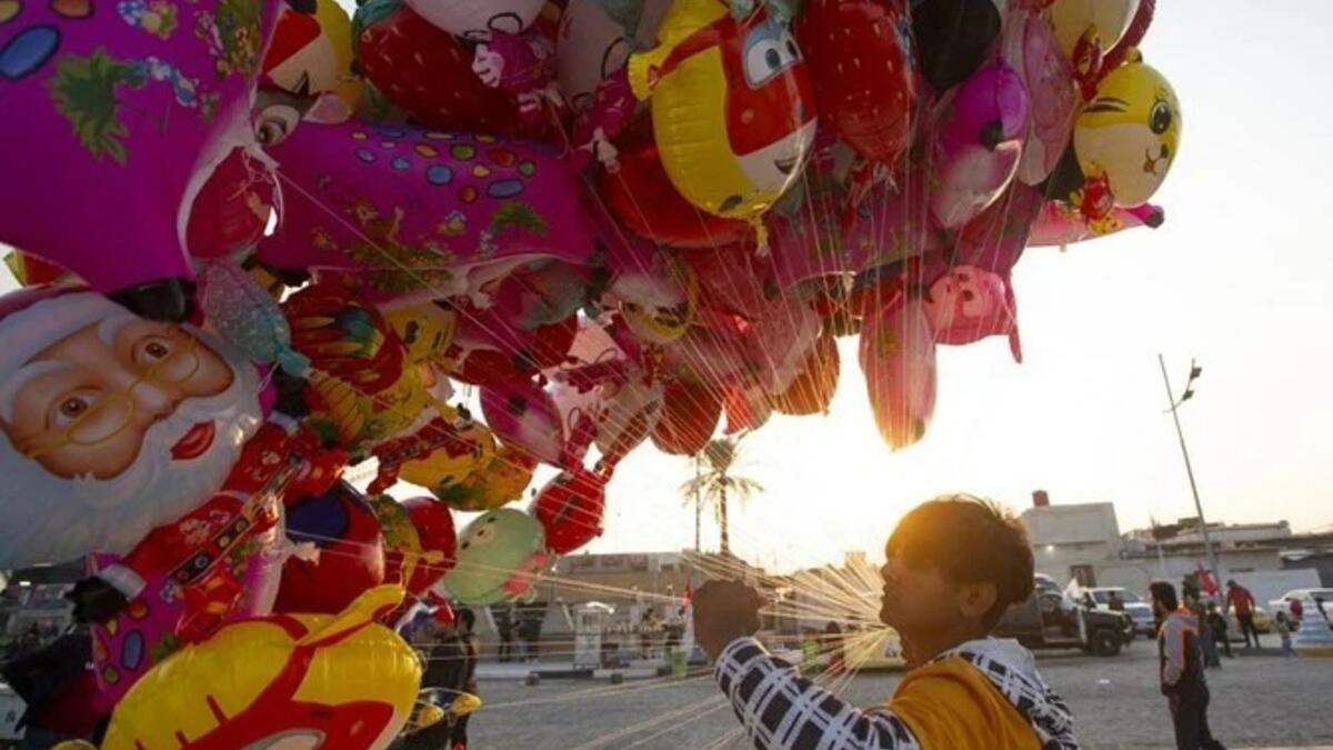 رجل يبيع البالونات على طول الواجهة البحرية لنهر شط العرب في مدينة البصرة الجنوبية، جنوبي بغداد، في 31 ديسمبر 2022، قبل حلول العام الجديد. (أ ف ب)