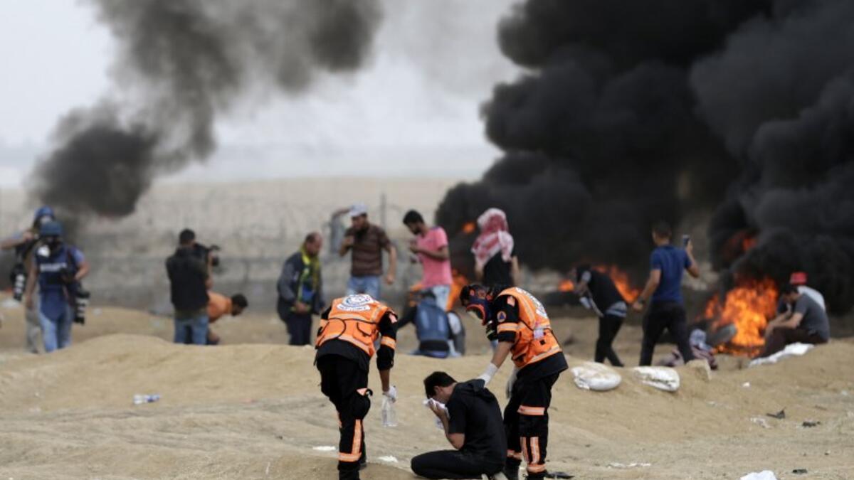 Palestinian protester react to teargas fumes during clashes with Israeli forces along the border with the Gaza strip east of Gaza City on May 4, 2018, on the sixth straight Friday of mass demonstrations calling for the right to return to their historic homelands. (MAHMUD HAMS / AFP)
