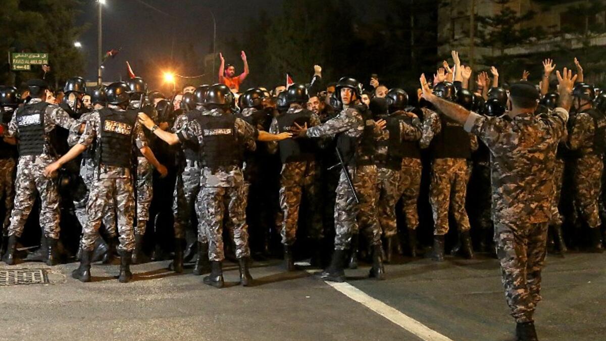 Demonstrators confront anti-riot policemen as they protest against against a proposed income tax draft law in front of the Prime Minister's office in Amman, late on June 1, 2018. 
STRINGER / AFP