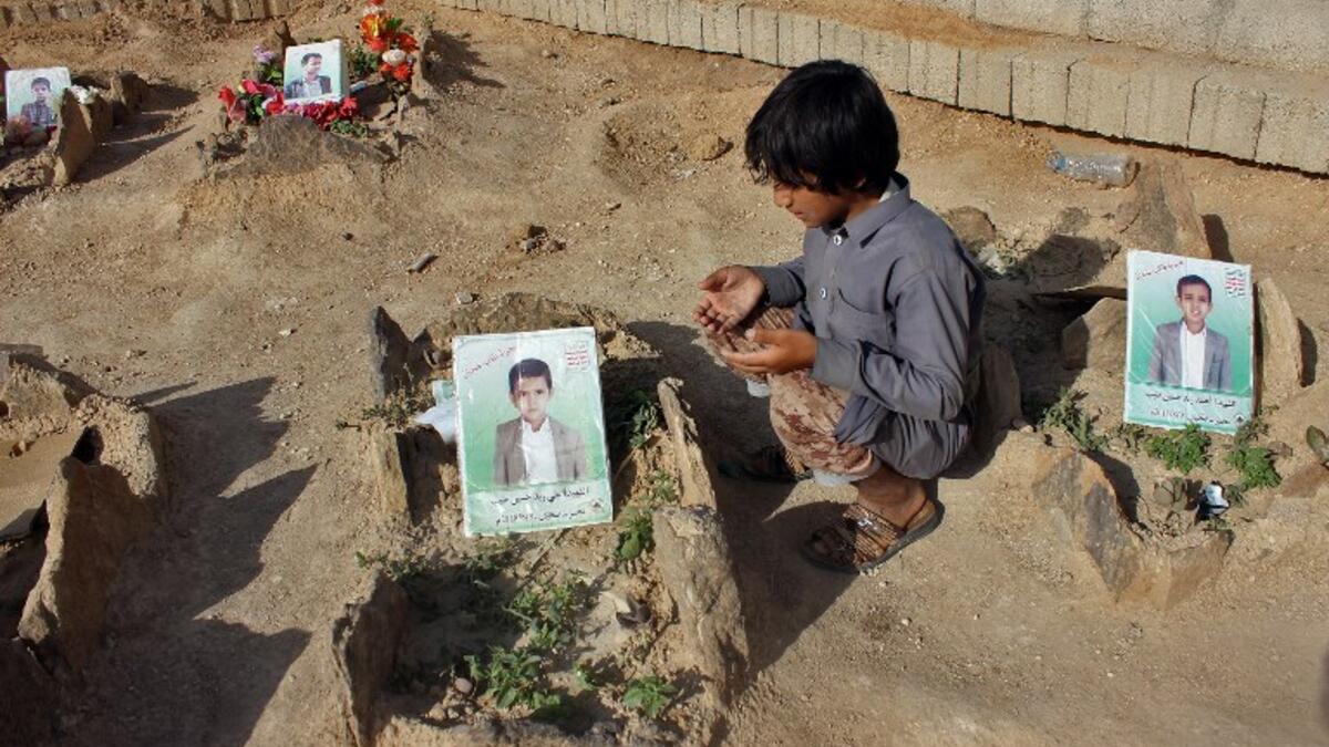 A Yemeni child recites a prayer by the graves of schoolboys who were killed while on a bus that was hit by a Saudi-led coalition air strike on the Dahyan market in August, at a cemetery in the Huthi rebels' stronghold province of Saada on September 4, 2018. 
STRINGER / AFP