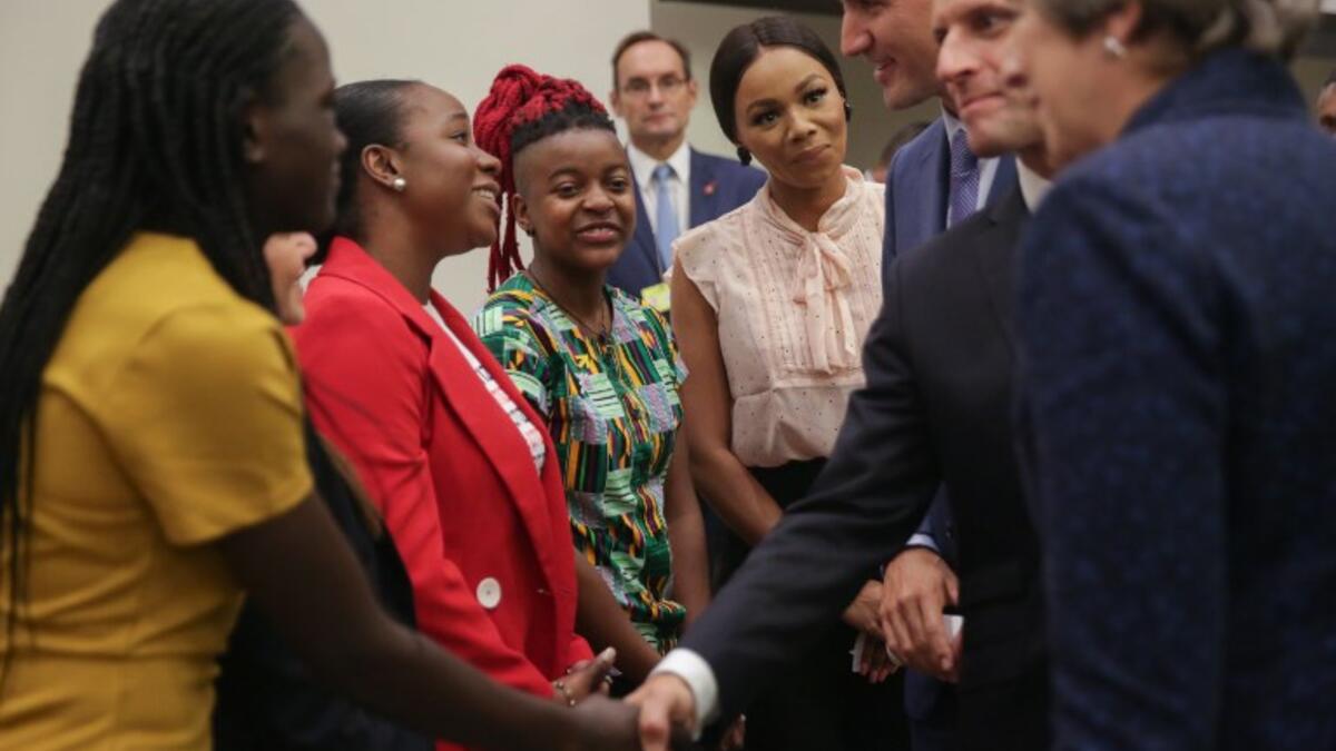 A woman reacts as British Prime Minister Theresa May (L), French President Emmanuel Macron (C) and Canadian Prime Minister Justin Trudeau (R) greet a group of women ahead the start of a Girl Education event at UN headquarters during the General Assembly of the United Nations in New York, September 25, 2018. 
AMR ALFIKY / AFP / POOL