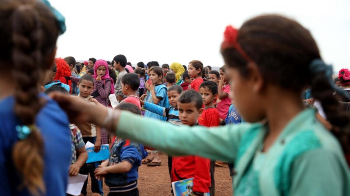 Syrian children who fled with their families from the northern countryside of Hama, line up in the yard of the makeshift school of "Zuhur al-Mustaqbal" (in Arabic "Flowers of the Future") in al-Jeneinah camp for displaced people in the village of Atme, in Syria's mostly rebel-held northern Idlib province, on October 1, 2018. Aaref WATAD / AFP