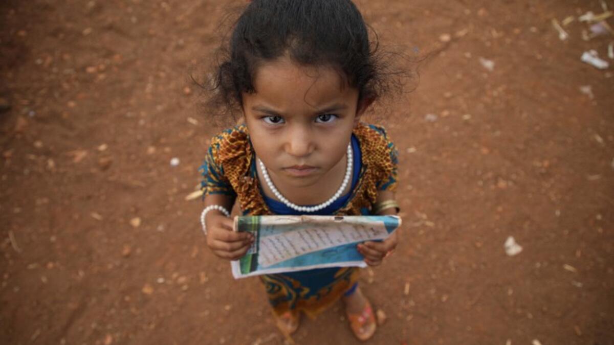 A Syrian child who fled with her family from the northern countryside of Hama, holds a book in the yard of the makeshift school of "Zuhur al-Mustaqbal" (in Arabic "Flowers of the Future") in al-Jeneinah camp for displaced people in the village of Atme, in Syria's mostly rebel-held northern Idlib province, on October 1, 2018. Aaref WATAD / AFP