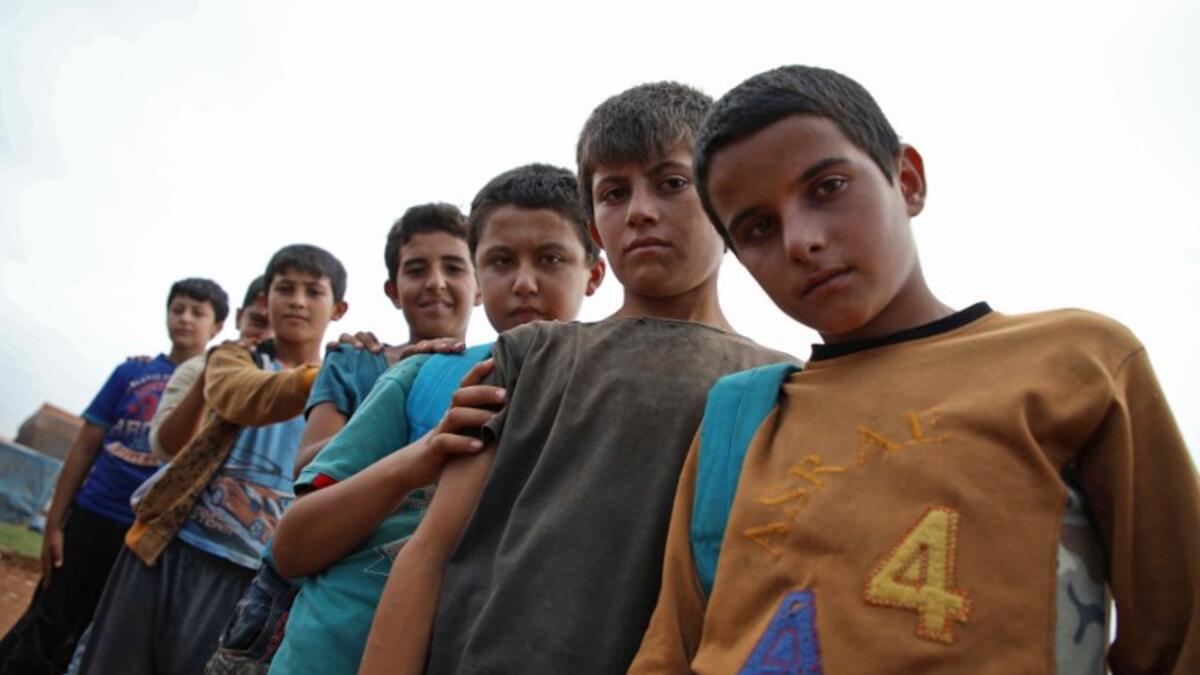 Syrian children who fled with their families from the northern countryside of Hama, pose in the yard of the makeshift school of "Zuhur al-Mustaqbal" (in Arabic "Flowers of the Future") in al-Jeneinah camp for displaced people in the village of Atme, in Syria's mostly rebel-held northern Idlib province, on October 1, 2018. Aaref WATAD / AFP
