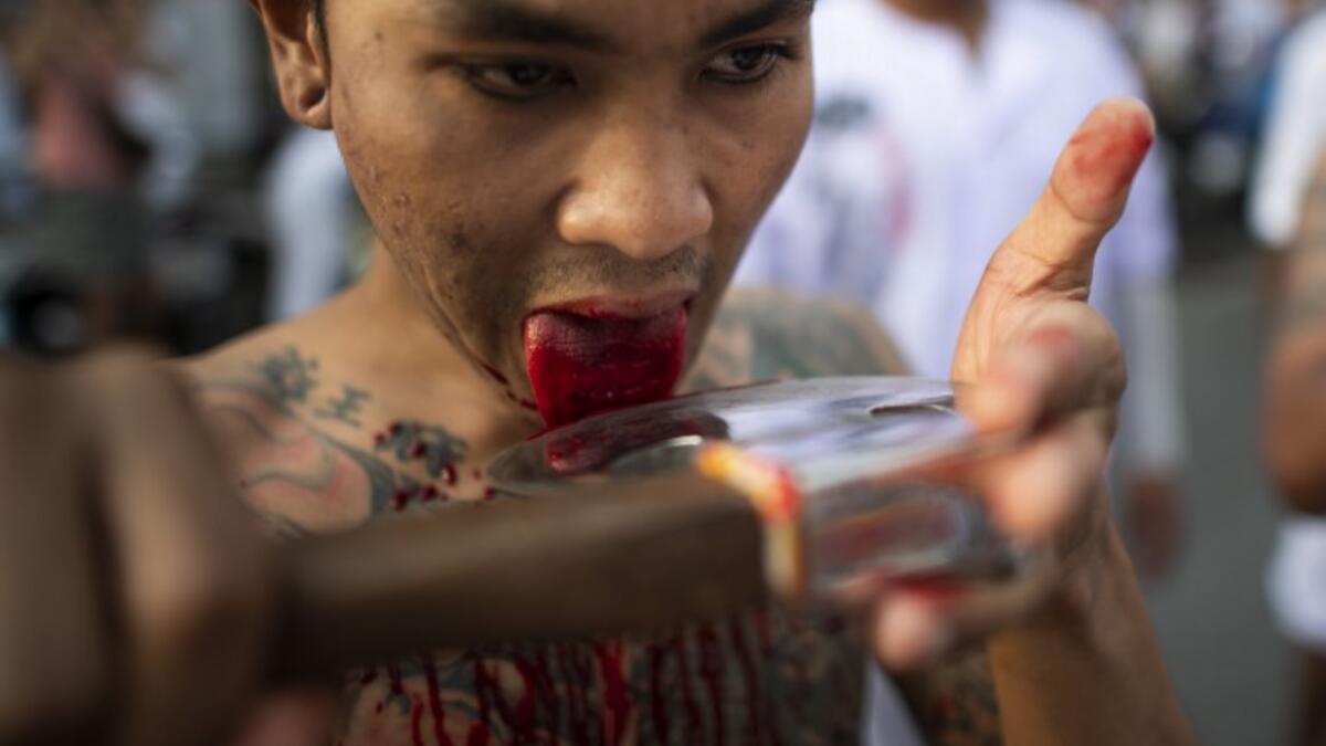 A devotee of the Loem Hu Thai Su shrine cuts his tongue on an axe as he parades during the annual Vegetarian Festival in Phuket on October 12, 2018. Jewel SAMAD/AFP