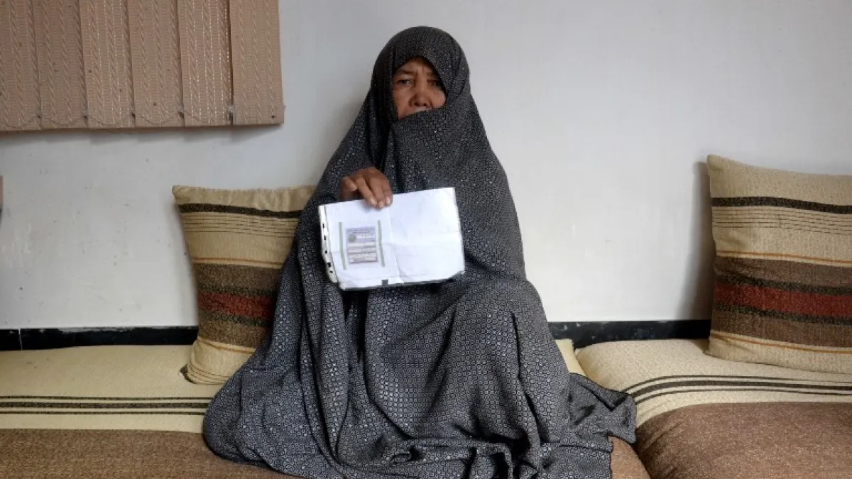 In this photo taken on October 11, 2018. Afghan housewife Fatimah, 55, poses for a picture as she holds her ID card or Tazkira registered to vote in the upcoming parliamentary election, at her House in Mazar-i-Sharif. 
FARSHAD USYAN / AFP