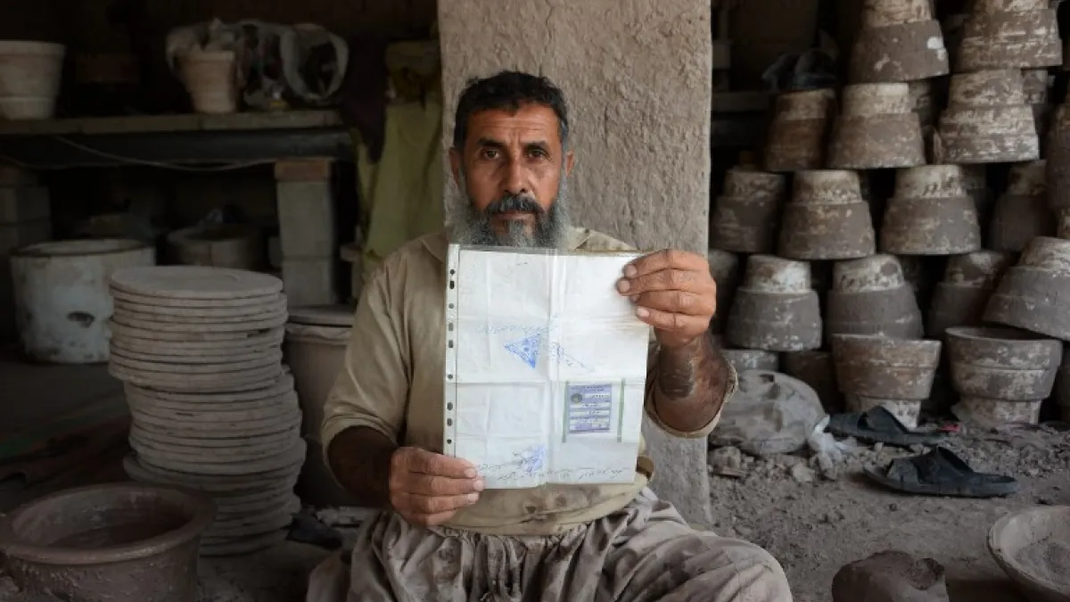In this photo taken on October 10, 2018.Afghan potter Shirin Agha, 45, poses for a picture as he holds his id card or Tazkira registered to vote in the upcoming parliamentary election at his workshop, on the outskirts of Jalalabad. 
NOORULLAH SHIRZADA / AFP