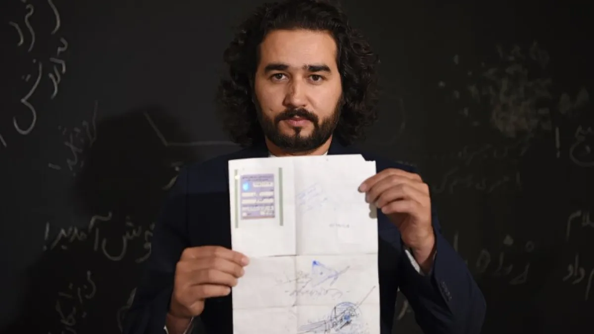 In this photo taken on October 8, 2018, Afghan co-founder and president of ArtLords Omaid Sharifi, 32, poses for a picture as he holds his id card or Tazkira registered to vote in the upcoming parliamentary election, in Kabul. 
WAKIL KOHSAR / AFP