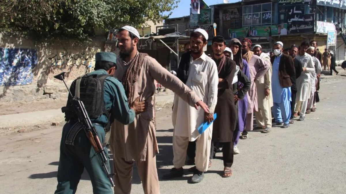An Afghan policeman searches voters before casting their votes at a polling centre for the country's legislative election in Khost Province on October 20, 2018. 
FARID ZAHIR / AFP