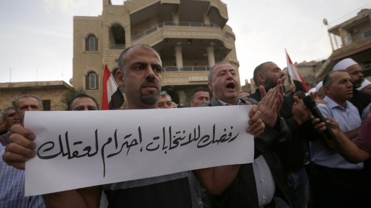 Druze residents of Majdal Shams in the Israeli-annexed Golan Heights protest against the municipal elections. Banner in Arabic reads: "Your rejection of the election is respecting your mind." (JALAA MAREY / AFP)