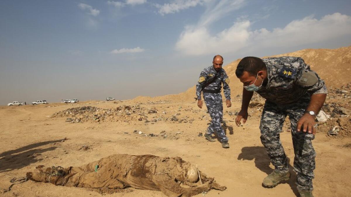 Members of the Iraqi forces check a body they pulled from a mass grave they discovered in the Hamam al-Alil area after they recaptured the area from Islamic State. (AHMAD AL-RUBAYE / AFP)