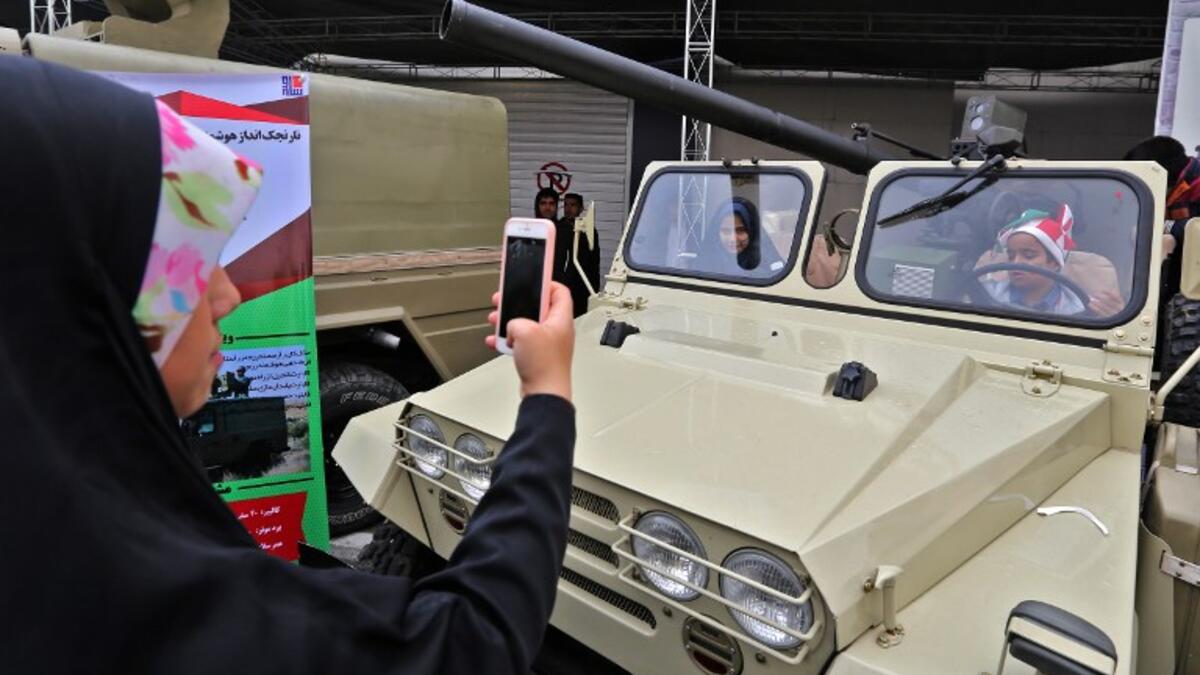 An Iranian woman takes pictures of children sitting in a four-wheel drive vehicle armed with a recoilless rifle, during commemorations of the 40th anniversary of Islamic Revolution in the capital Tehran on February 11, 2019. 
ATTA KENARE / AFP