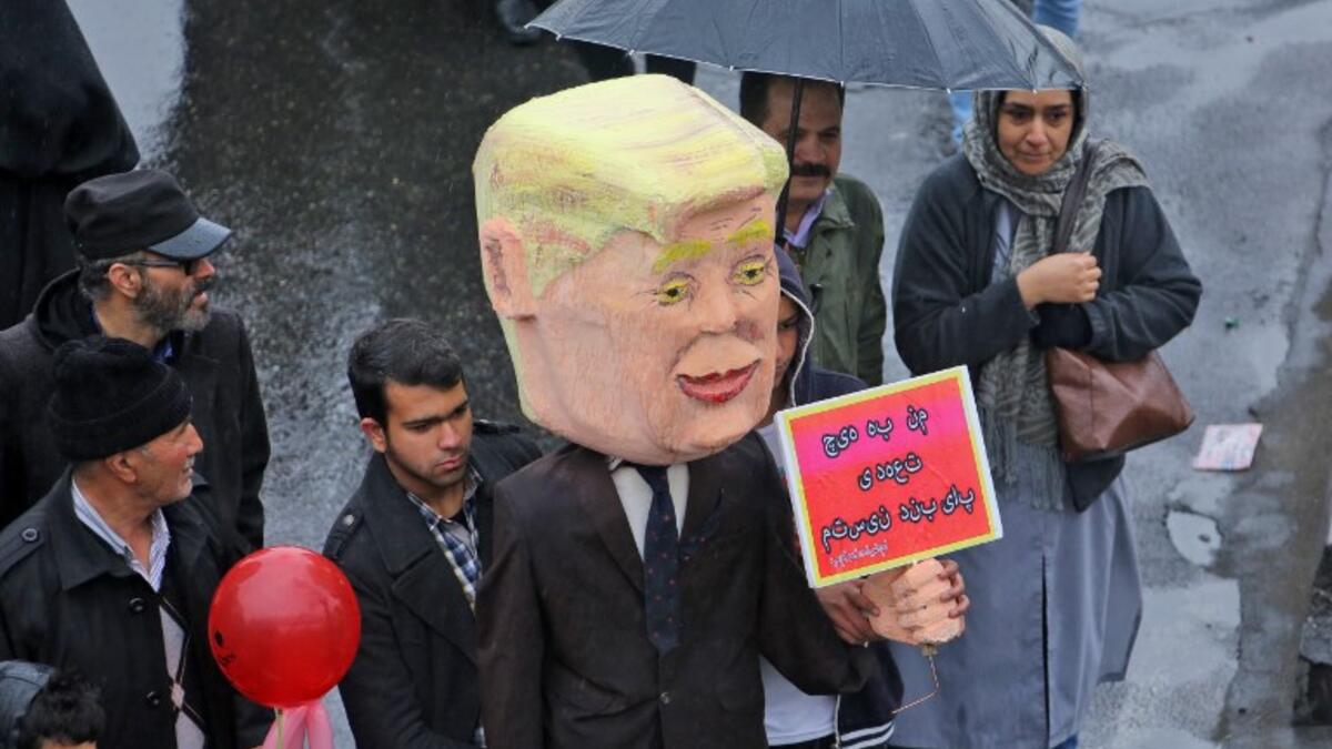 An Iranian man carries an effigy depicting US President Donald Trump carrying a sign reading in Persian "I am not bound by any commitment", during a ceremony celebrating the 40th anniversary of Islamic Revolution in the capital Tehran on February 11, 2019. 
ATTA KENARE / AFP