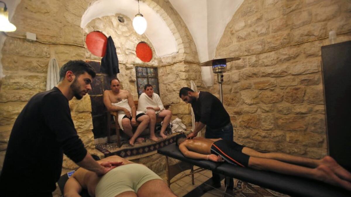 Men wait as others receive massages at the first traditional Turkish bath (Hammam) opening in the occupied Palestinian West Bank city of Hebron on March 11, 2019. 
HAZEM BADER / AFP