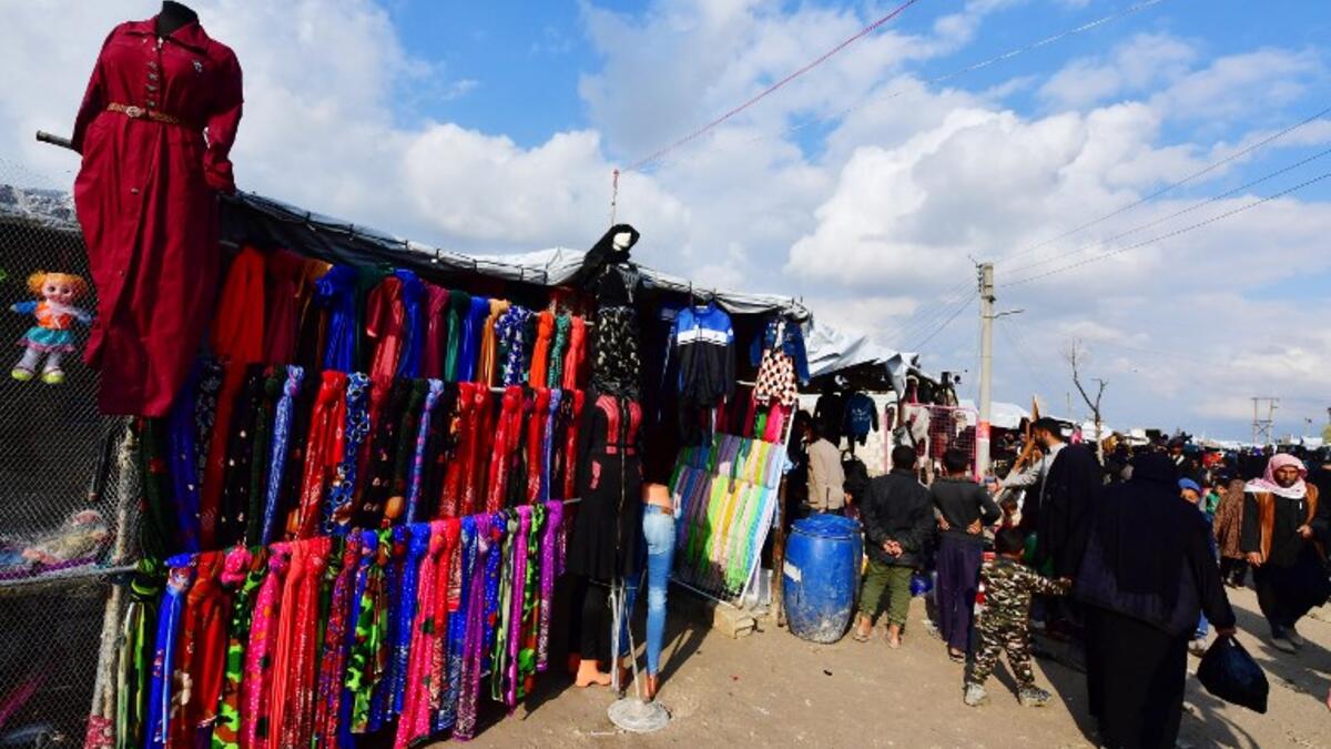People walk past clothing stalls in the souk or market of Al-Hol camp for displaced people in northeastern Syria
GIUSEPPE CACACE / AFP