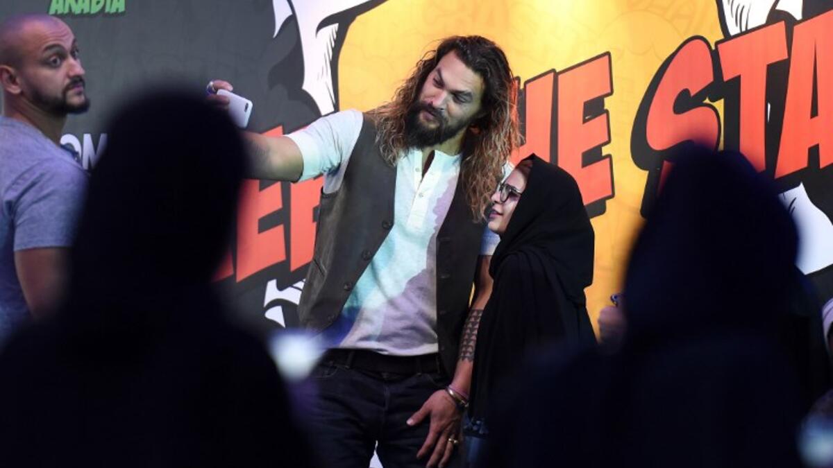 US actor Jason Momoa uses a cell phone to pose for a "selfie" photograph with a Saudi woman as they attend the first ever Comic-Con Arabia event held in the capital Riyadh on November 25, 2017. 
(FAYEZ NURELDINE / AFP)