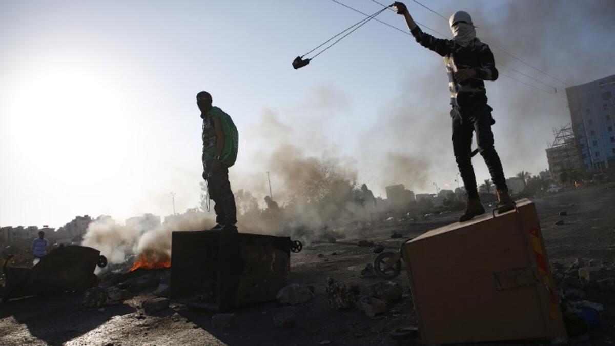 A Palestinian protestor uses a slingshot during clashes with Israeli forces near an Israeli checkpoint in the West Bank city of Ramallah. (ABBAS MOMANI / AFP)