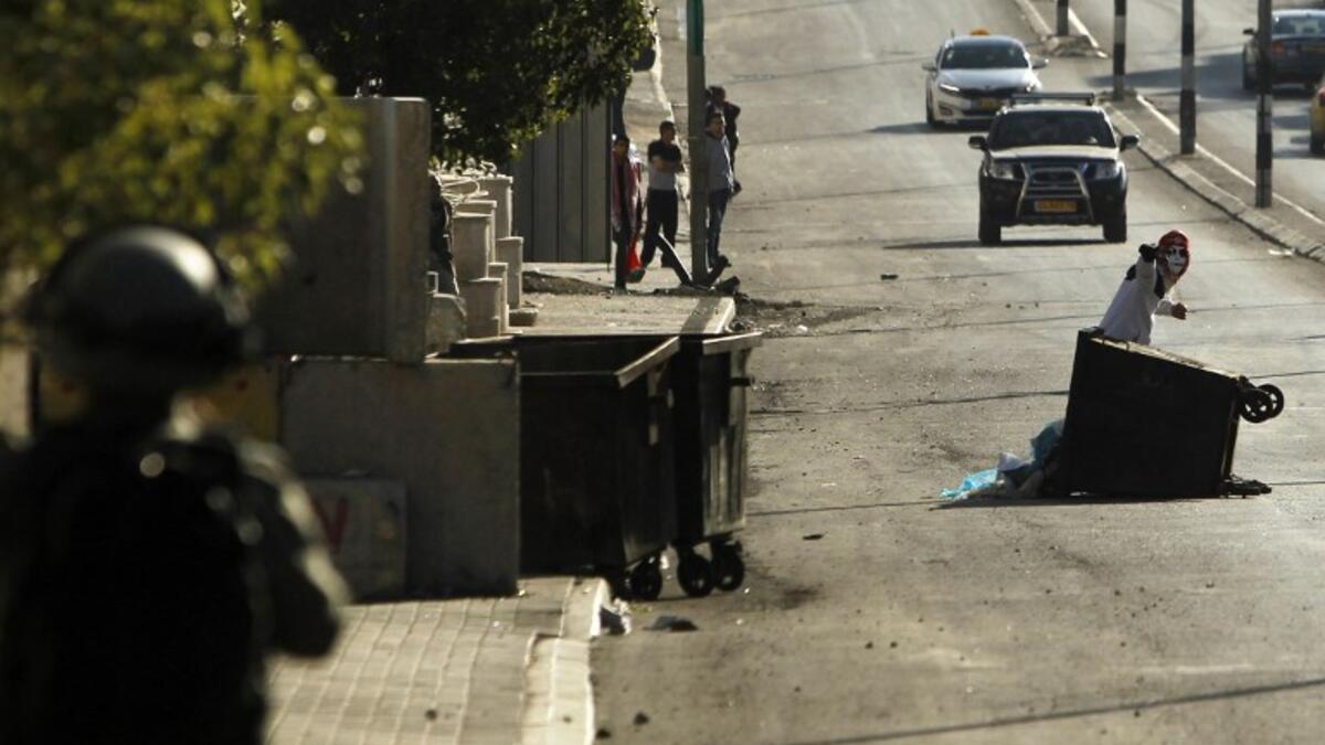 A member of the Israeli forces (L) holds a position as a Palestinian protestor throws stones during clashes following a demonstration by the Popular Front for the Liberation of Palestine (PFLP) in Bethlehem in the Israeli occupied West Bank. 
(Musa AL SHAER / AFP)