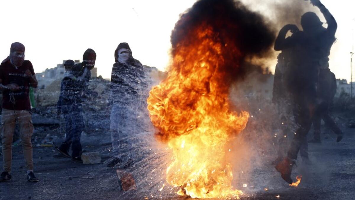 A Palestinian demonstrator kicks a burning tire during clashes with Israeli forces near an Israeli checkpoint in the West Bank city of Ramallah following the U.S. president's controversial recognition of Jerusalem as Israel's capital. 
(ABBAS MOMANI / AFP)