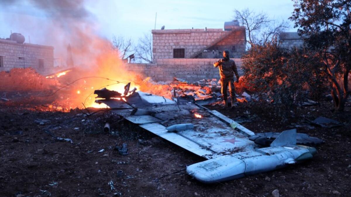 A picture taken on February 3, 2018, shows a Rebel fighter taking a picture of a downed Sukhoi-25 fighter jet in Syria's northwest province of Idlib. Rebel fighters shot down a Russian plane over Syria's northwest Idlib province and captured its pilot, the Syrian Observatory for Human Rights said. (OMAR HAJ KADOUR / AFP)