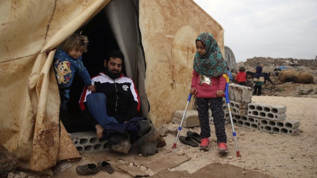 Maya Merhi (R) stands with the support of crutches next to her disabled father (C) outside their tent in the Internally Displaced Persons (IDP) camp of Serjilla in northwestern Syria next to Bab al-Hawa border crossing with Turkey.
Aaref WATAD / AFP