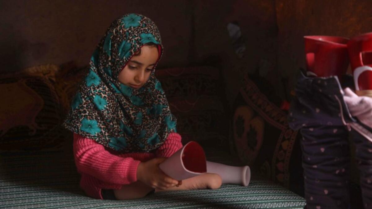 Syrian Maya Merhi poses for a picture next to her prosthetic legs that are decorated with the Turkish flag inside a tent at the Internally Displaced Persons (IDP) camp of Serjilla in northwestern Syria. 
Aaref WATAD / AFP