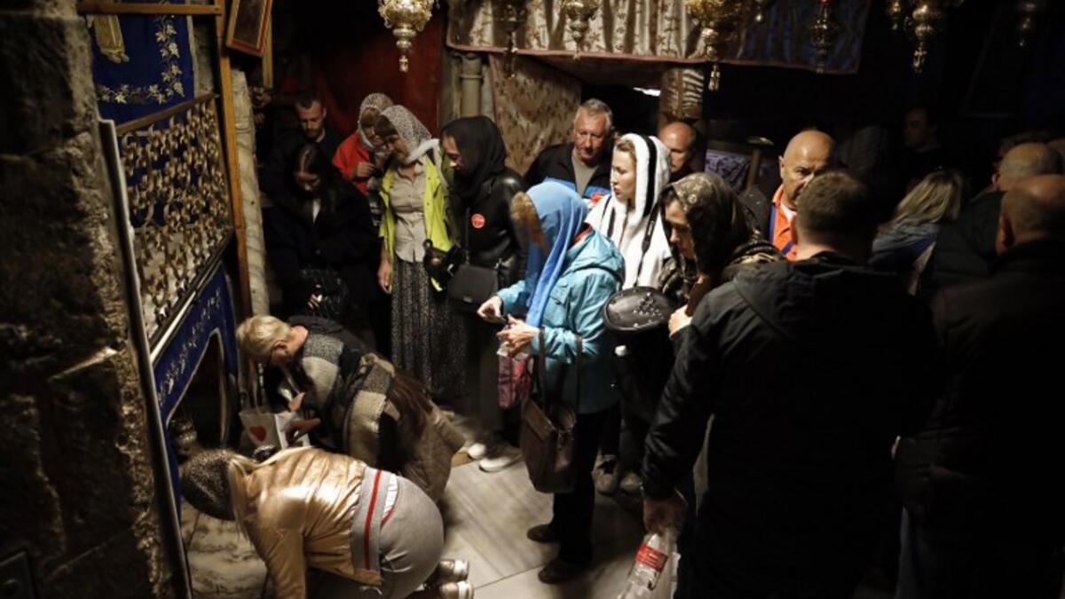 A group of tourists and pilgrims visit the Grotto, believed to be the exact spot where Jesus Christ was born, as others pray at the Church of the Nativity in the West Bank city of Bethlehem. Thomas Coex/AFP