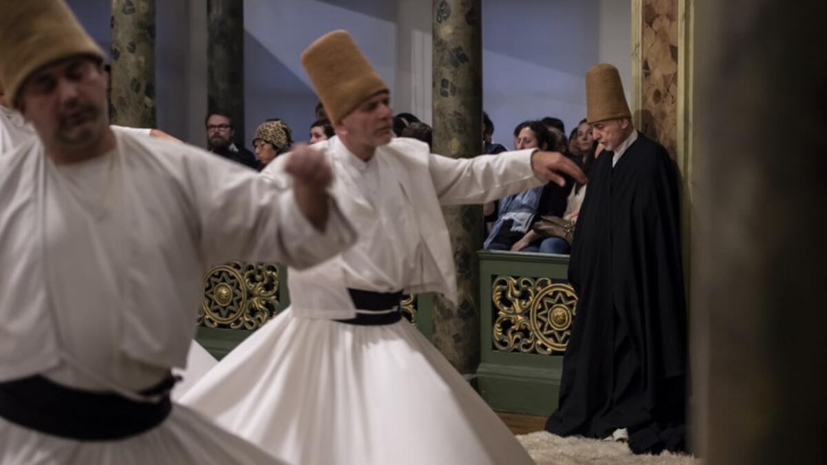 People look at whirling dervishes performing during a ceremony marking the anniversary of the death of Jelaleddin Mevlana Rumi, Sufi mystic, poet and founder of the sufism on December 16, 2018 at Galata Mevlihanesi in Istanbul. 
Yasin AKGUL / AFP