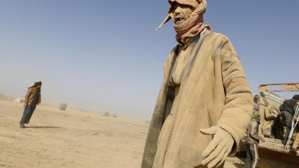A man covered in dust gestures as people who fled battles between Syrian Democratic Forces (SDF) and ISIS fighters in the Syrian village of Baghouz, arrive after crossing a desert in the back of a truck to a region controlled by the SFD in the countryside of the Deir Ezzor province, Delil SOULEIMAN / AFP