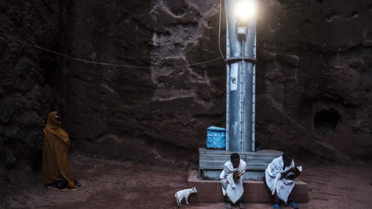 Ethiopian Orthodox devotees sit on a pillar of the shelter that protects from erosion the structure of the rock-hewn church of Saint Emmanuel in Lalibela, Ethiopia
EDUARDO SOTERAS / AFP