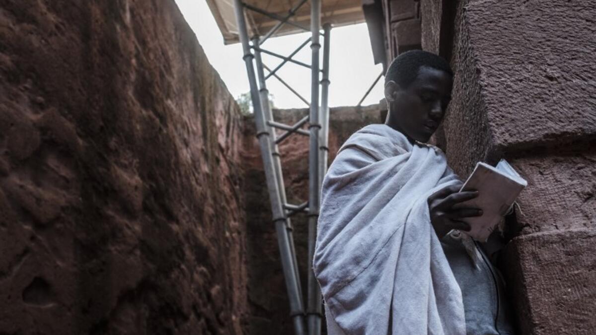 An Ethiopian Orthodox devotee reads a bible near the pillar of a shelter protecting from erosion the rock-hewn structure of the church of Saint Emmanuel in Lalibela, Ethiopia
EDUARDO SOTERAS / AFP