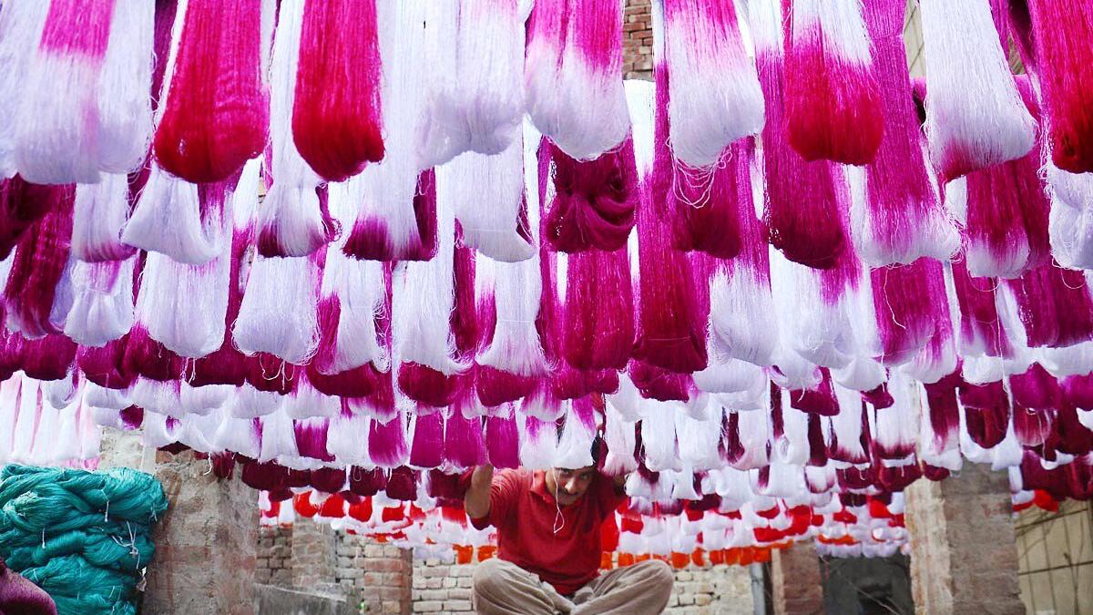 A Pakistani worker dries fabric threads after dyeing them at a factory in Lahore (Twitter)