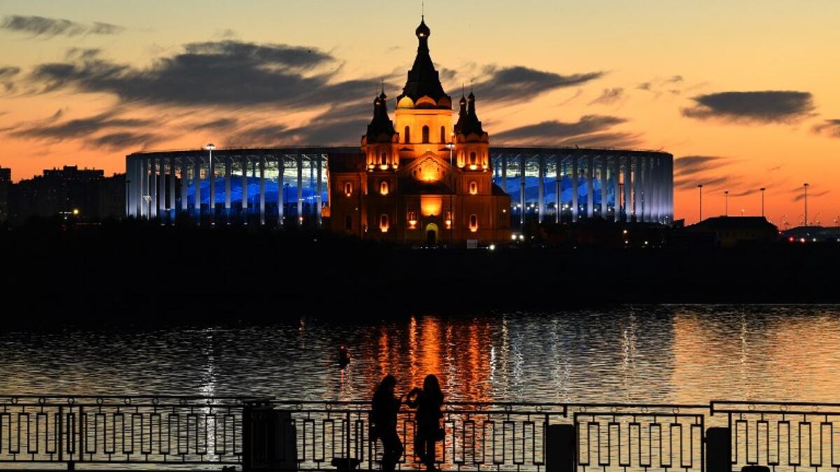 Young women stand in front of the Nizhny Novgorod stadium situated behind the cathedral of Alexandr Nevskiy in the city of Nizhny Novgorod, during the Russia 2018 World Cup on June 16, 2018. 
Johannes EISELE / AFP