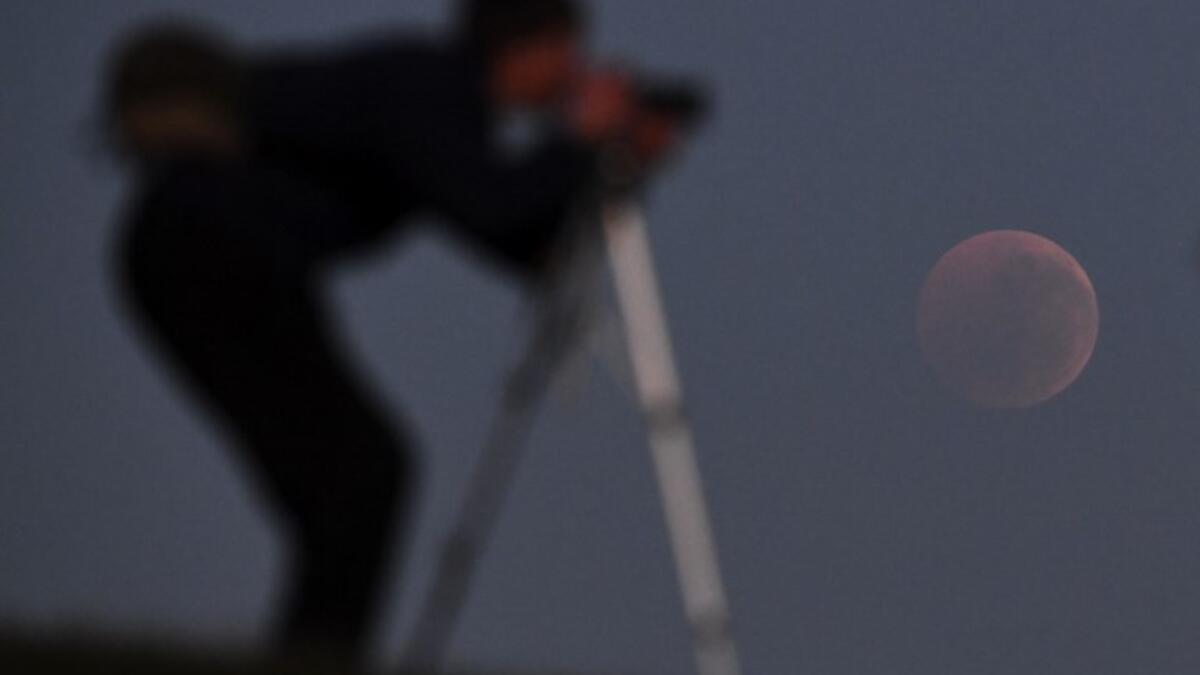 People gather to watch a "blood moon" eclipse in Melbourne on July 28, 2018. (AFP/WILLIAM WEST)