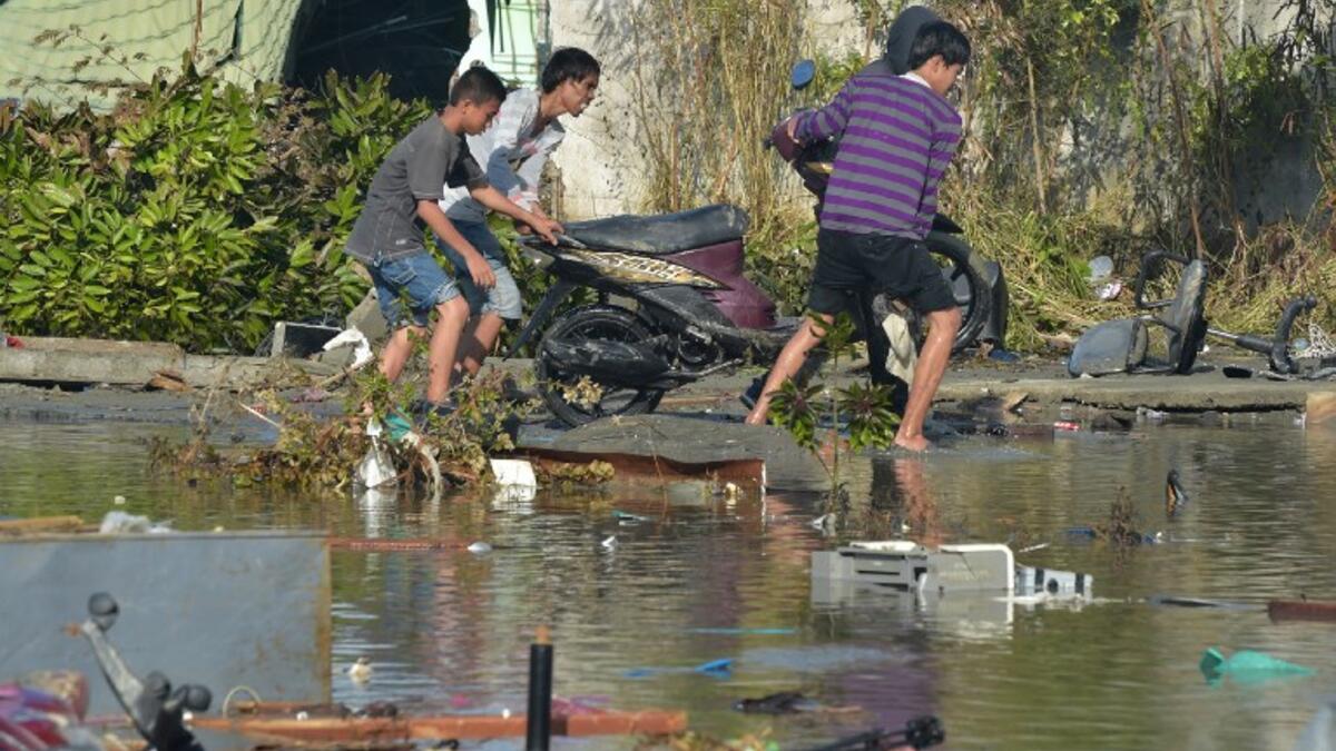 People salvage a motorcyle in Palu, Indonesia's Central Sulawesi on September 30, 2018, following the September 28 earthquake and tsunami.(ADEK BERRY / AFP)