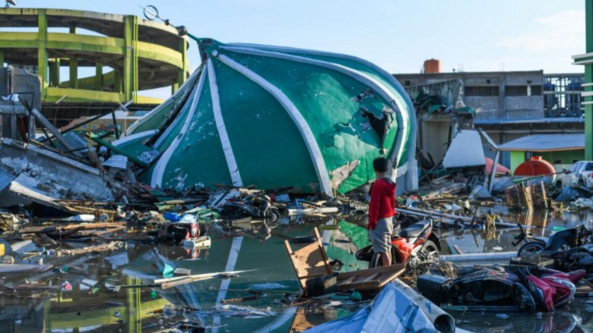 An earthquake victim salvages useable items near a collapsed mosque in Palu, Indonesia's Central Sulawesi on October 1, 2018. (JEWEL SAMAD / AFP)